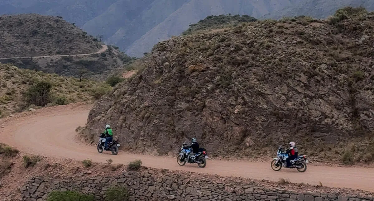 Foto distante de pilotos enfileirados em suas motocicletas nas estrada de terra