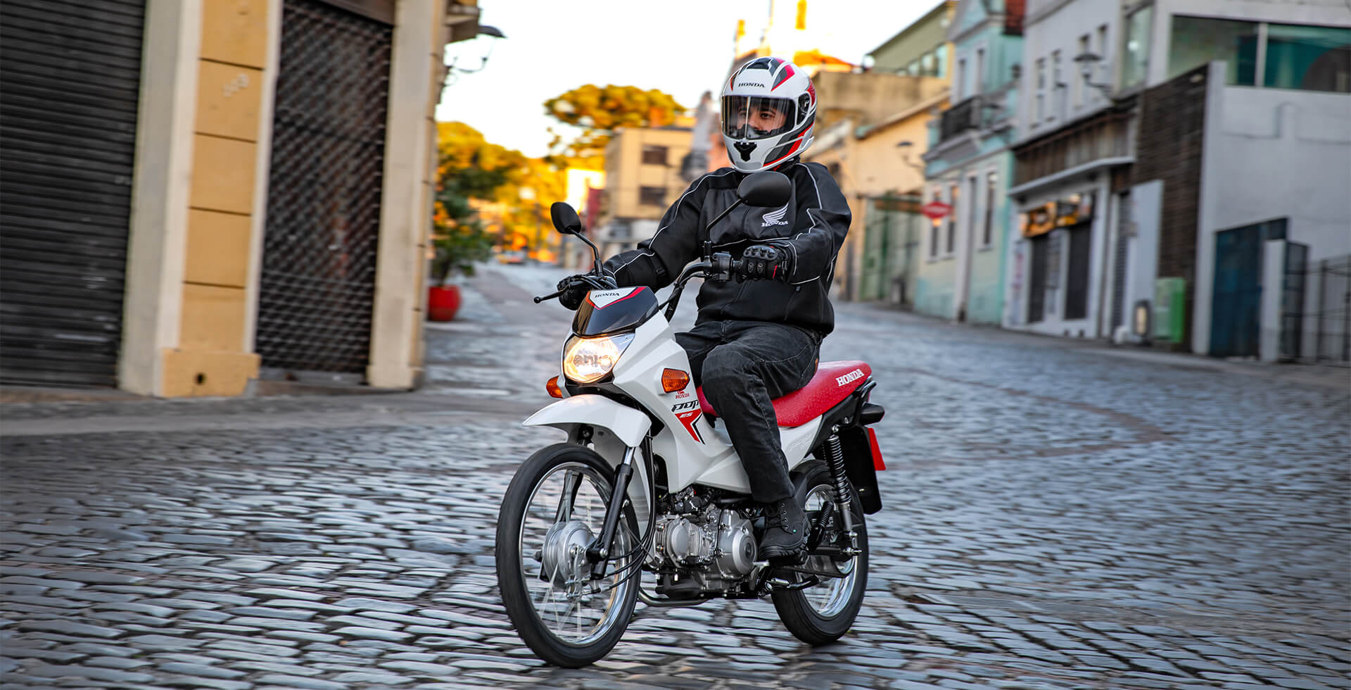 Homem na cidade pilotando a Moto Honda POP 110i ES Branco Ross White