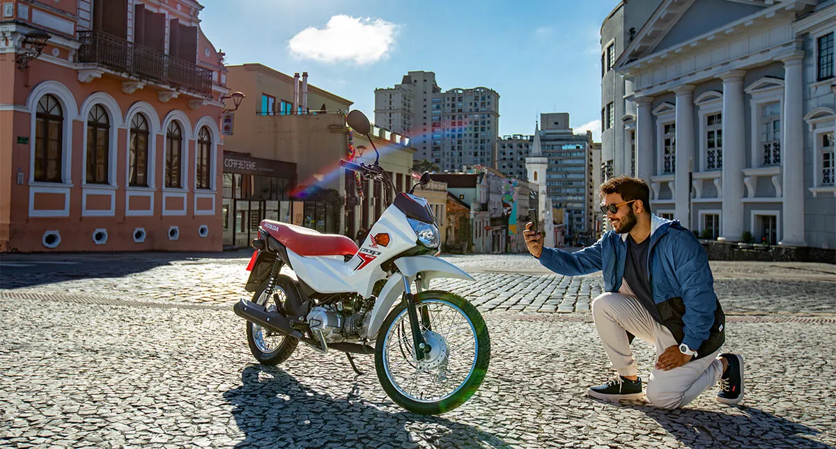 Homem tirando foto da motocicleta Pop 110i ES Branco Ross White 