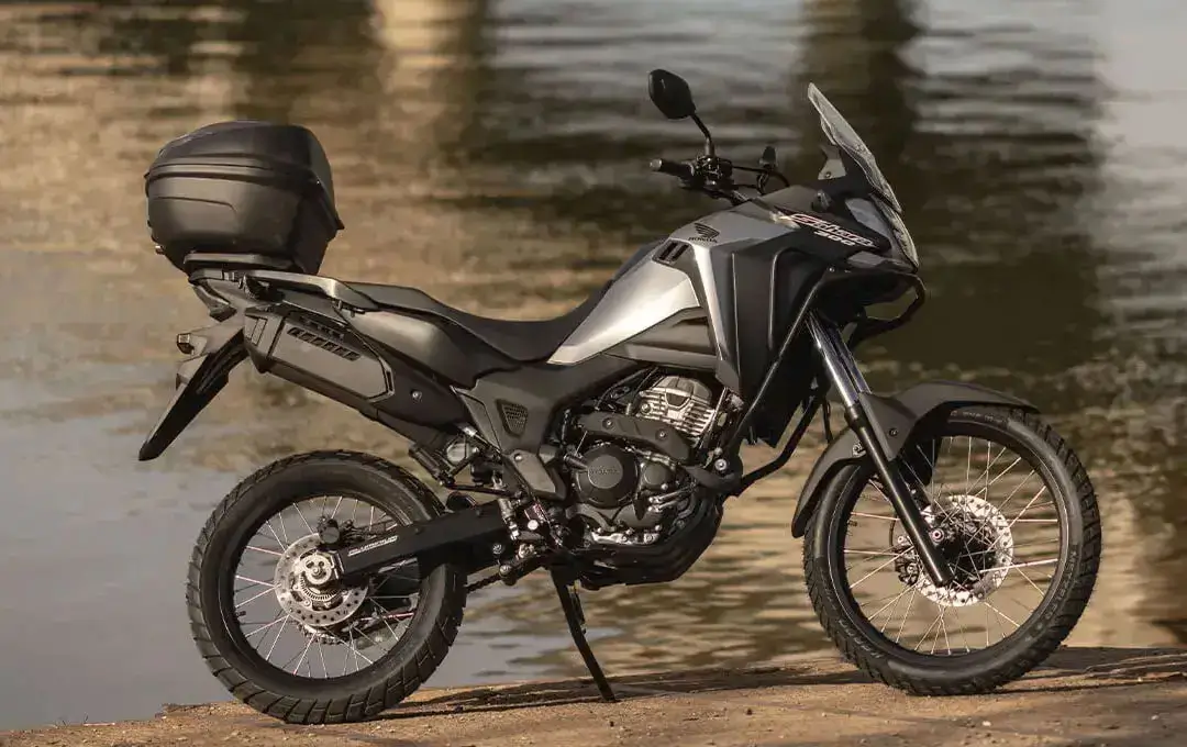 Honda Sahara 300 prata com lago ao fundo