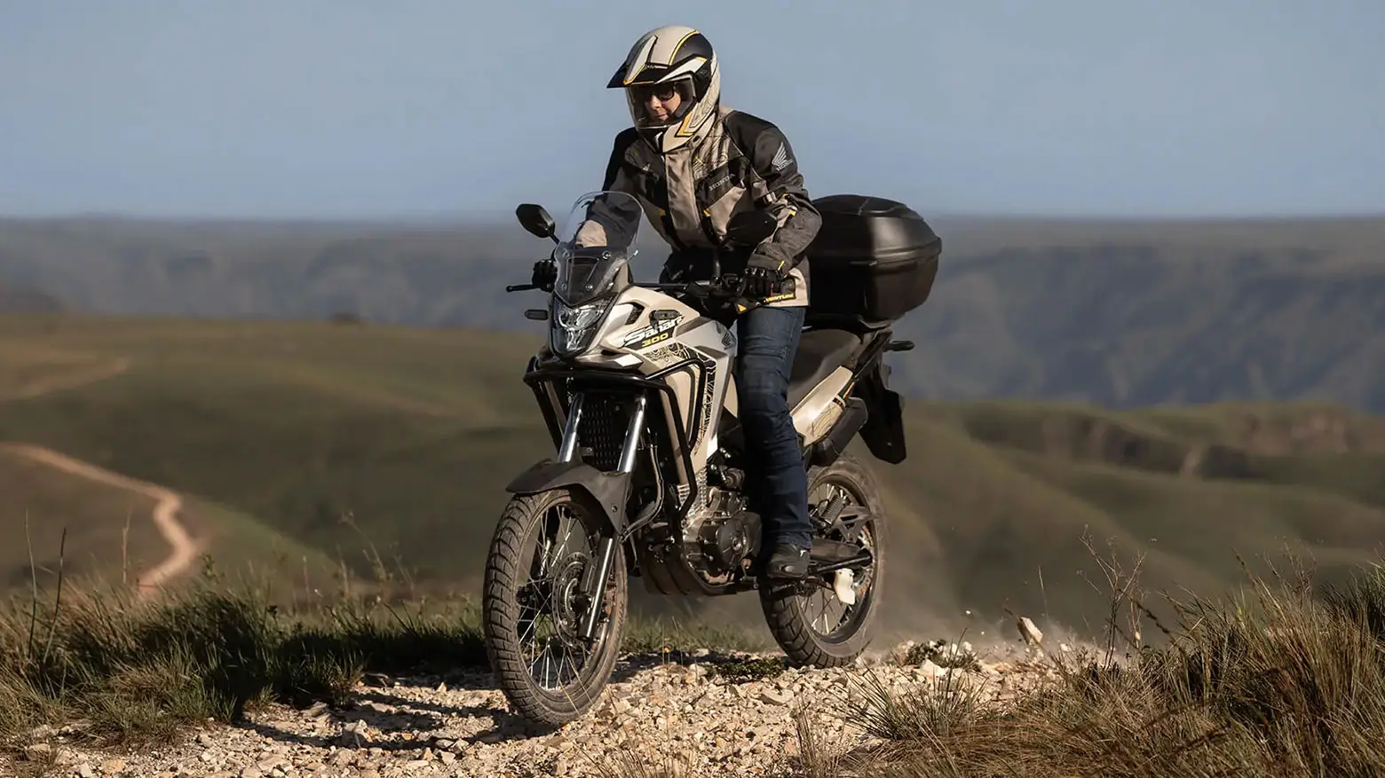 Piloto em pé em moto Honda Sahara 300 Adventure em trilha de areia
