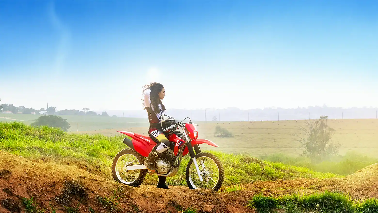 Motociclista olhando para o horizonte sentado na Honda CRF 250F