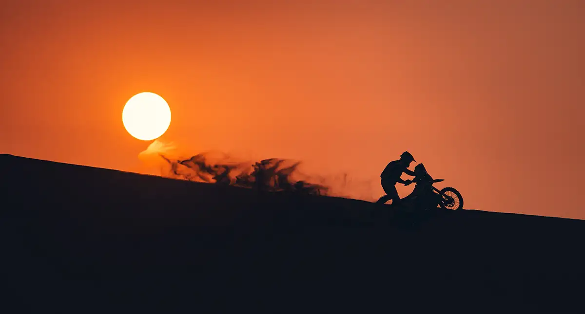Piloto empurrando uma off-road no topo de uma duna