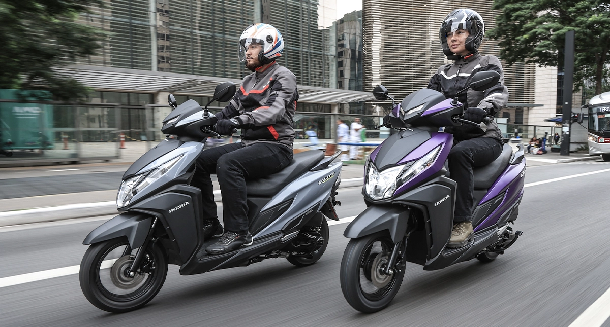 Duas pessoas pilotando scooters lado a lado