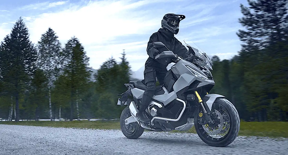 Motociclista andando em estrada de terra cercada por árvores