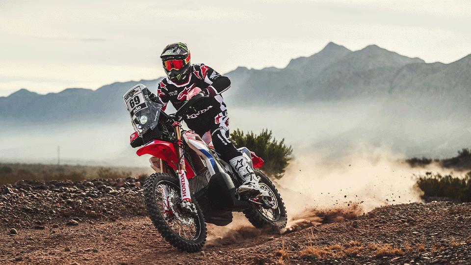 Piloto Honda acelerando moto em estrada de terra