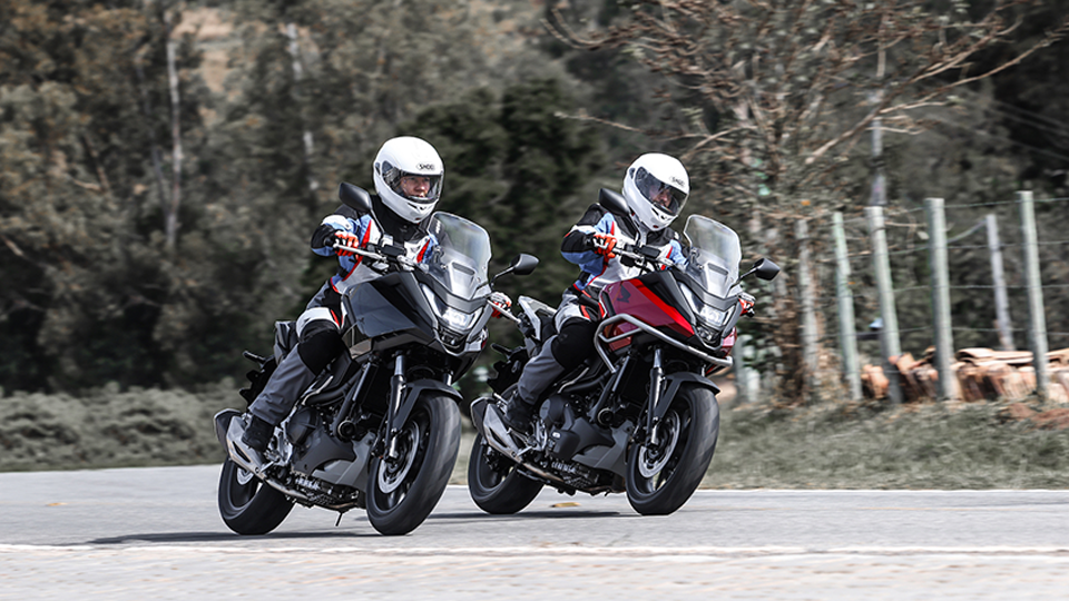 Dois motoqueiros em motos Honda fazendo curva 